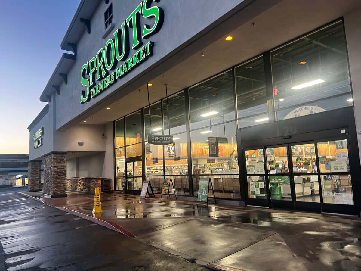 Freshly pressure-washed storefront entrance and sidewalk at a grocery-anchored shopping center at dawn